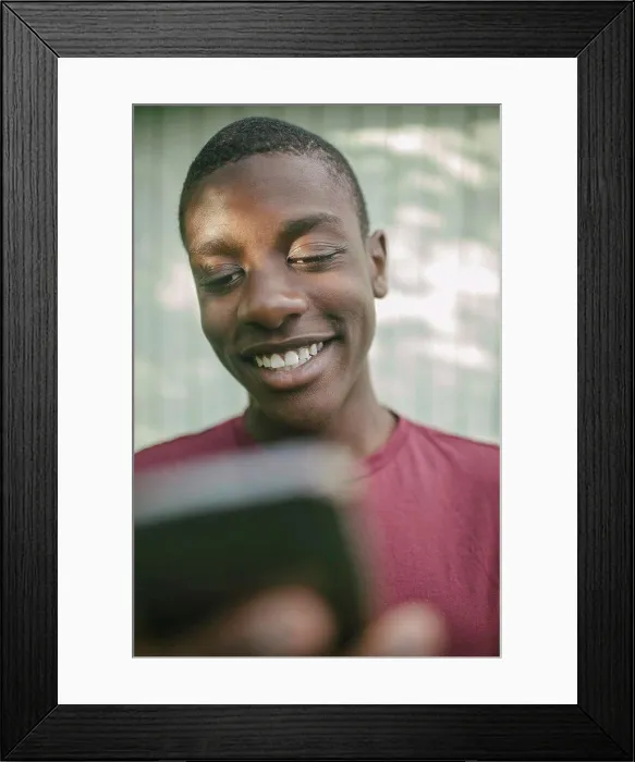 Framed Print : Smiling boy using mobile in backyard
