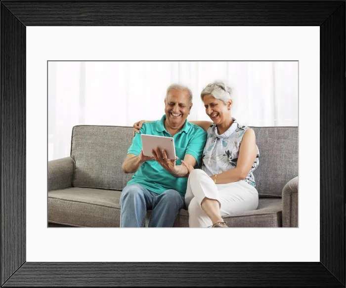 Framed Print : Senior couple sitting on sofa using digital tablet Framed Print : Senior couple sitting on sofa using digital tablet