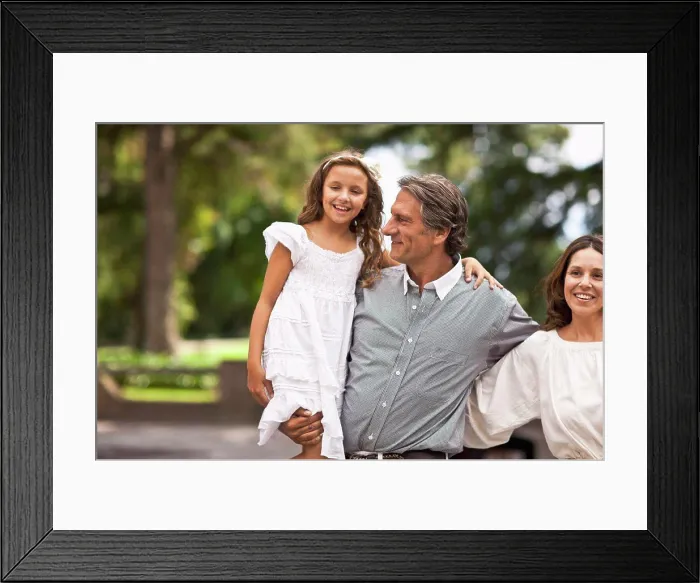 Framed Print : Father holds his daughter in his arms while standing beside his wife