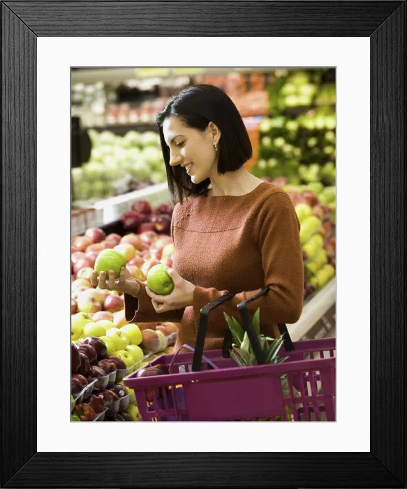 Framed Print : Woman holding green apples at grocery store with shopping basket