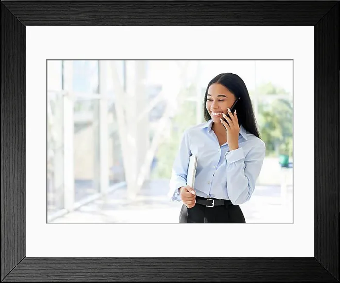 Framed Print : Smiling African American businesswoman talking on phone in open space modern office with panoramic windows background Framed Print : Smiling African American businesswoman talking on phone in open space modern office with panoramic windows background
