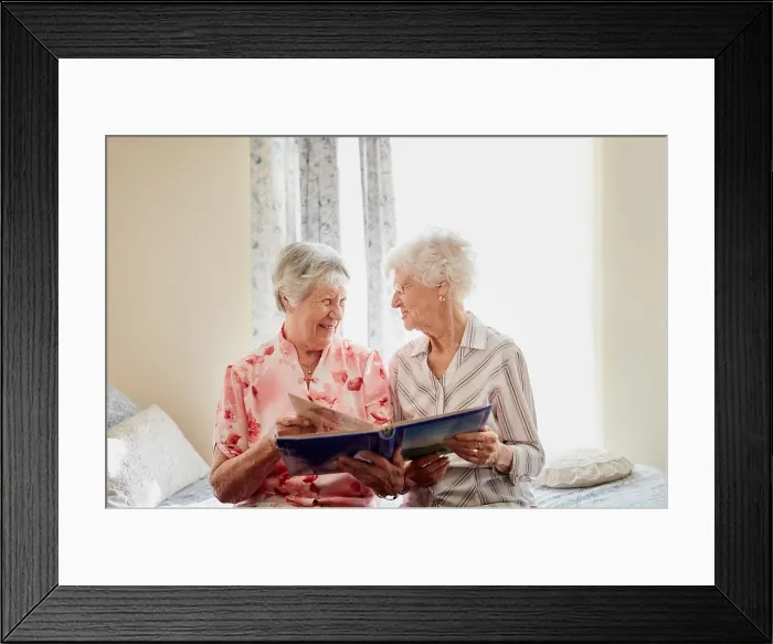 Framed Print : Friends, photo album and happy senior women on bed with memory