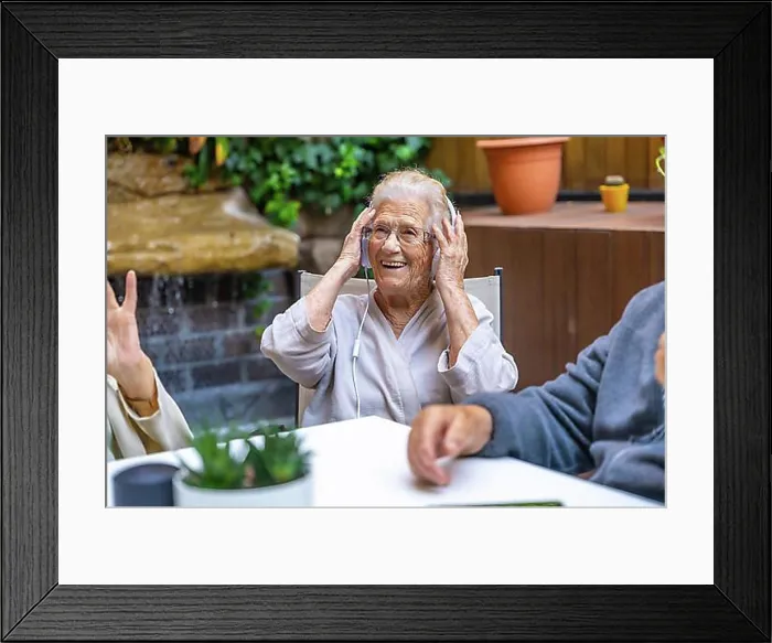 Framed Print : Happy seniors using headphones and having fun in a nursing home