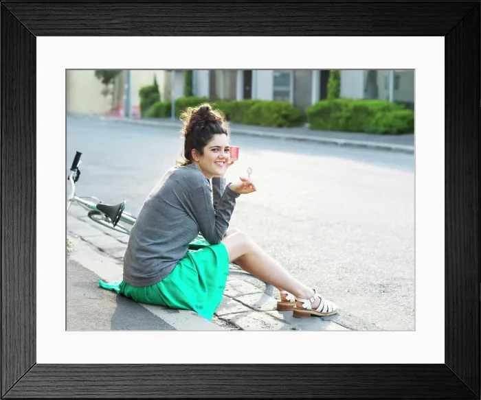 Framed Print : Young woman enjoying a sunny day with a refreshing popsicle by the roadside