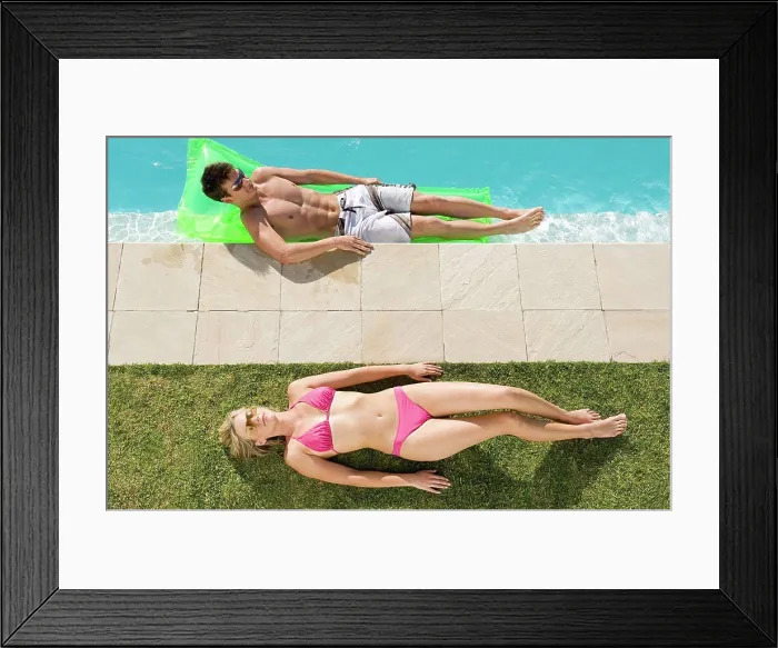 Framed Print : Couple sunbathing at the pool