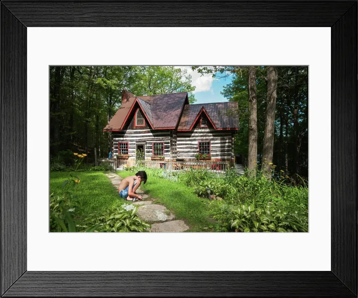 Framed Print : Boy squatting on a path to a log cabin cottage on a summer day Framed Print : Boy squatting on a path to a log cabin cottage on a summer day