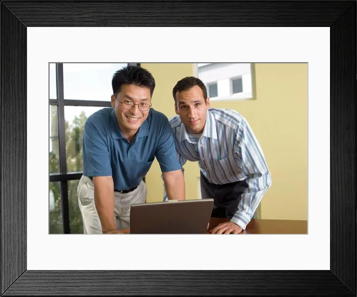 Framed Print : Portrait of two businessmen standing in front of a laptop Framed Print : Portrait of two businessmen standing in front of a laptop