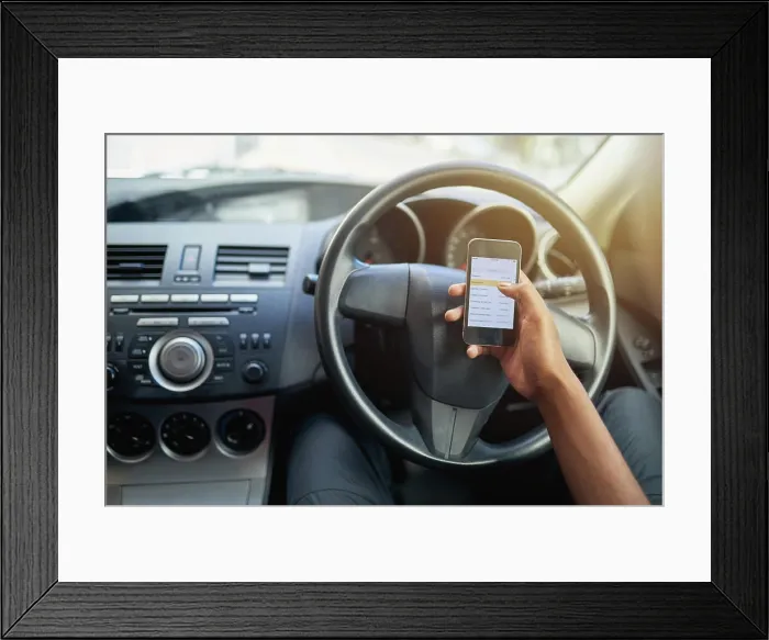 Framed Print : Phone, texting and driving with hands of person on steering wheel with scroll