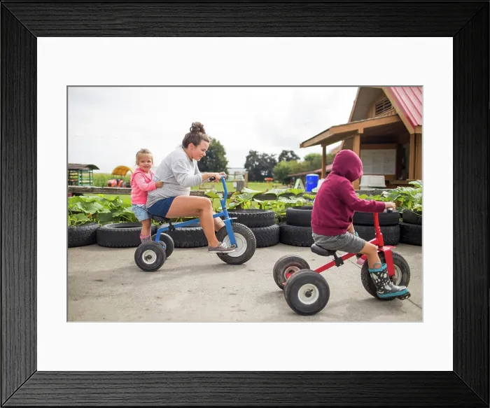 Framed Print : Mother biking on tricycles with her two kids outdoors