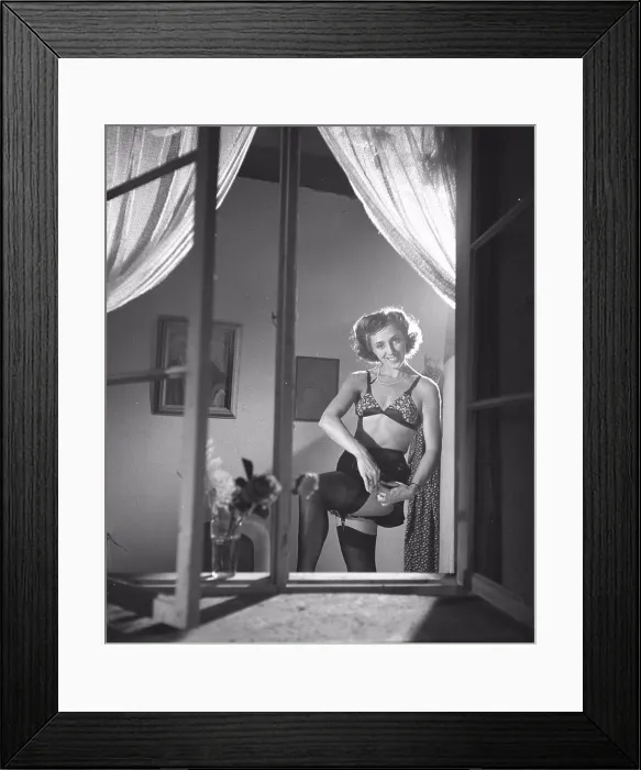 Framed Print : Nylon stockings in the 1940s. A woman is showing how well her nylon stockings fit on her legs