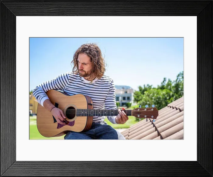 Framed Print : Attractive man with long hair playing acoustic guitar outdoors