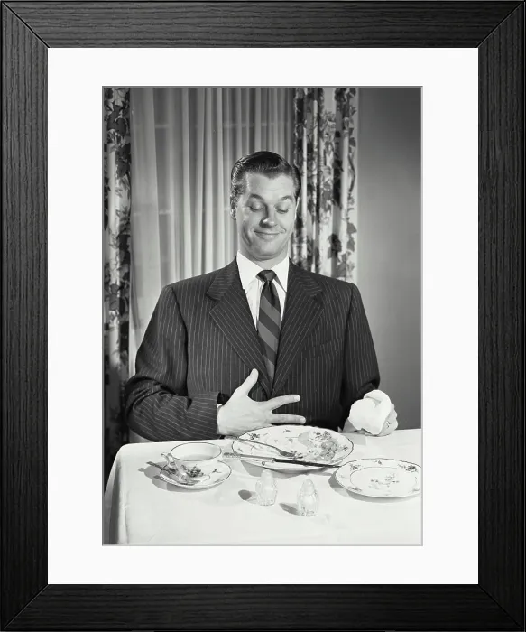 Framed Print : Vintage photograph. Man at table holding full stomach with empty plates Framed Print : Vintage photograph. Man at table holding full stomach with empty plates