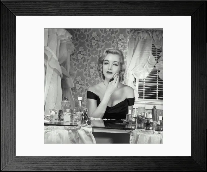 Framed Print : Young woman applying make-up to face Framed Print : Young woman applying make-up to face