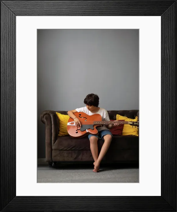 Framed Print : Boy playing guitar in living room Framed Print : Boy playing guitar in living room