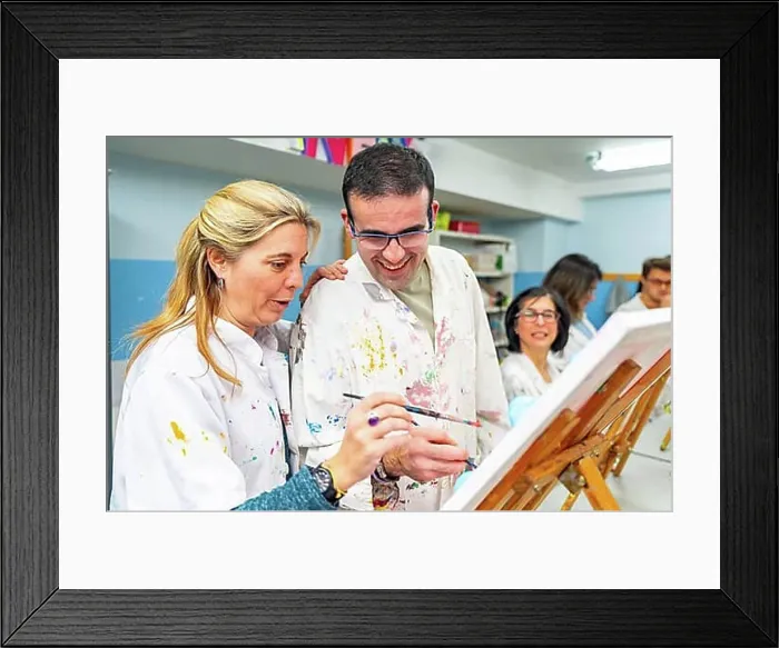 Framed Print : Instructor helping a disabled man during painting class in a center for people with special needs Framed Print : Instructor helping a disabled man during painting class in a center for people with special needs