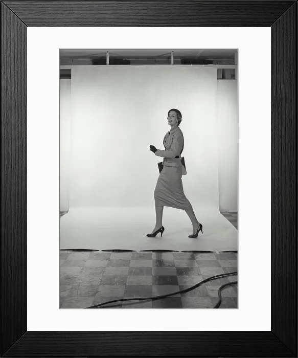 Framed Print : Vintage Photograph. Full length view of woman wearing light grey skirt and jacket and hat on white studio background