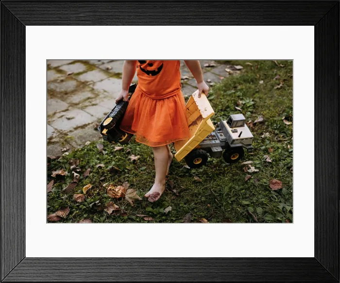 Framed Print : Little girl playing with toy trucks and tractors during autumn Framed Print : Little girl playing with toy trucks and tractors during autumn