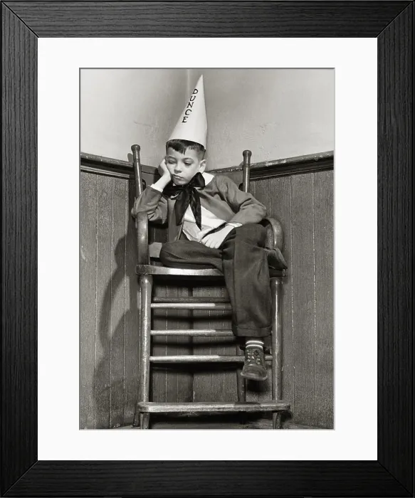 Framed Print : Low angle view of a boy wearing a dunce cap Framed Print : Low angle view of a boy wearing a dunce cap