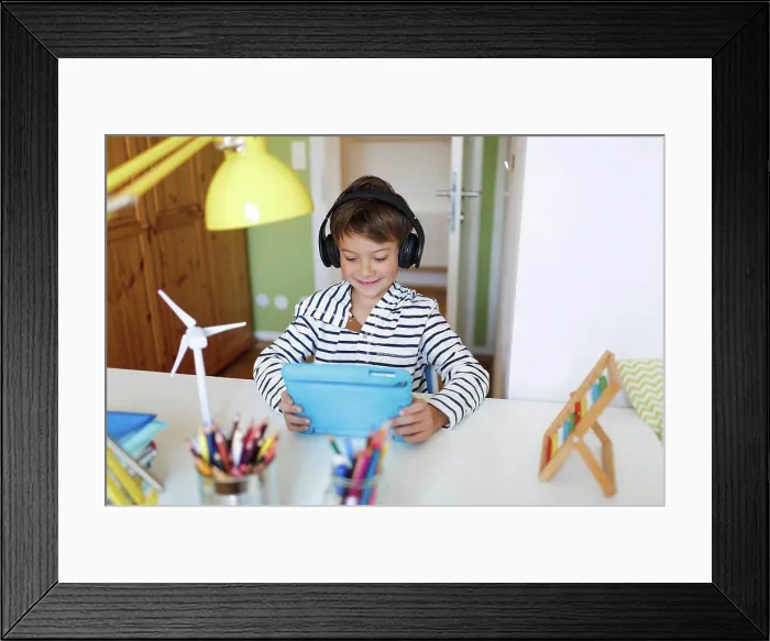 Framed Print : Boy doing homeschooling and using tablet and headphones at home Framed Print : Boy doing homeschooling and using tablet and headphones at home