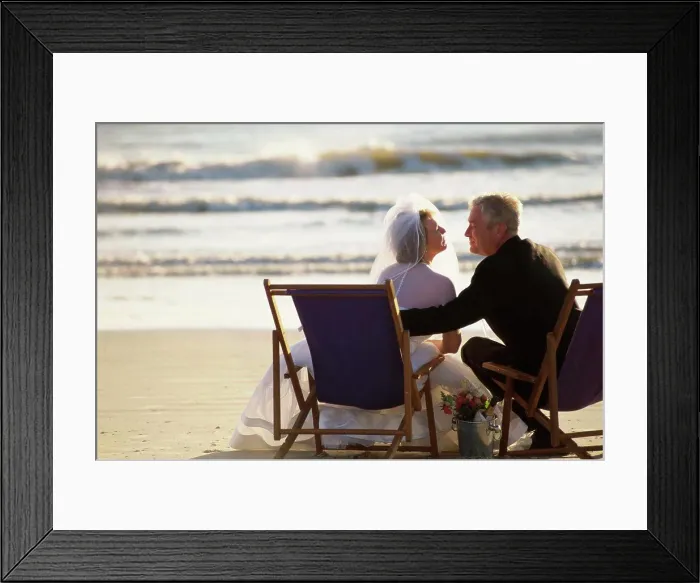 Framed Print : Rear view of a bride and bridegroom sitting on the beach Framed Print : Rear view of a bride and bridegroom sitting on the beach
