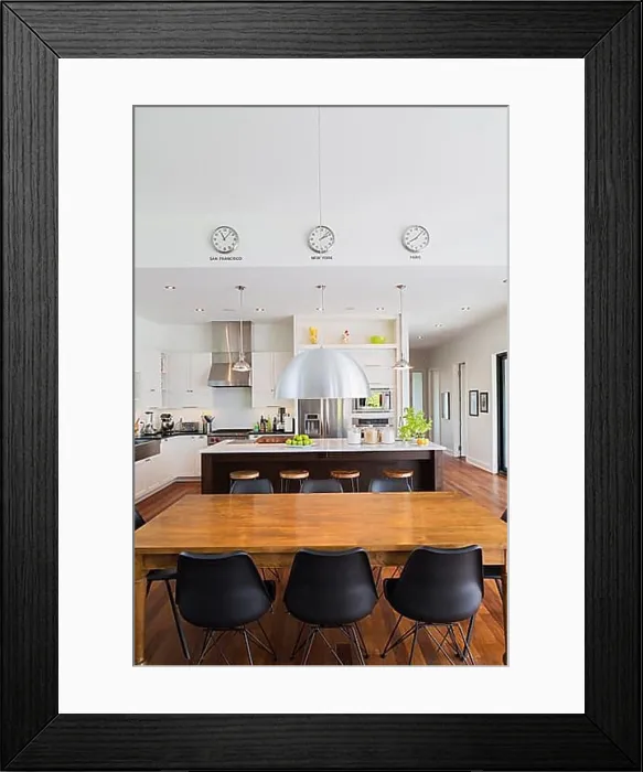 Framed Print : Open-concept dining and kitchen area with antique dining table with black leather and plastic chairs Framed Print : Open-concept dining and kitchen area with antique dining table with black leather and plastic chairs