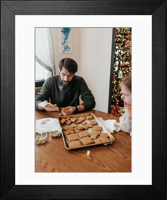 Framed Print : Father and daughter work together to build gingerbread house Framed Print : Father and daughter work together to build gingerbread house