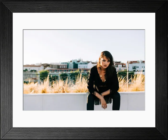 Framed Print : Beautiful stylish woman in black outfit sitting with city landscape in Lisbon on sunny day