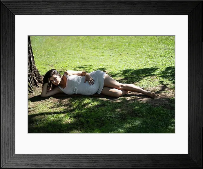 Framed Print : Pregnant Latina woman lying on the grass in a park Framed Print : Pregnant Latina woman lying on the grass in a park