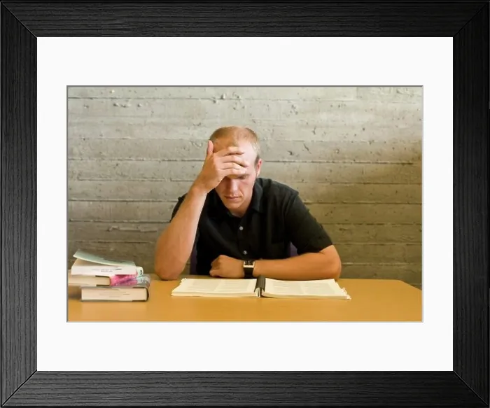 Framed Print : Young man reading and studying in a library Framed Print : Young man reading and studying in a library