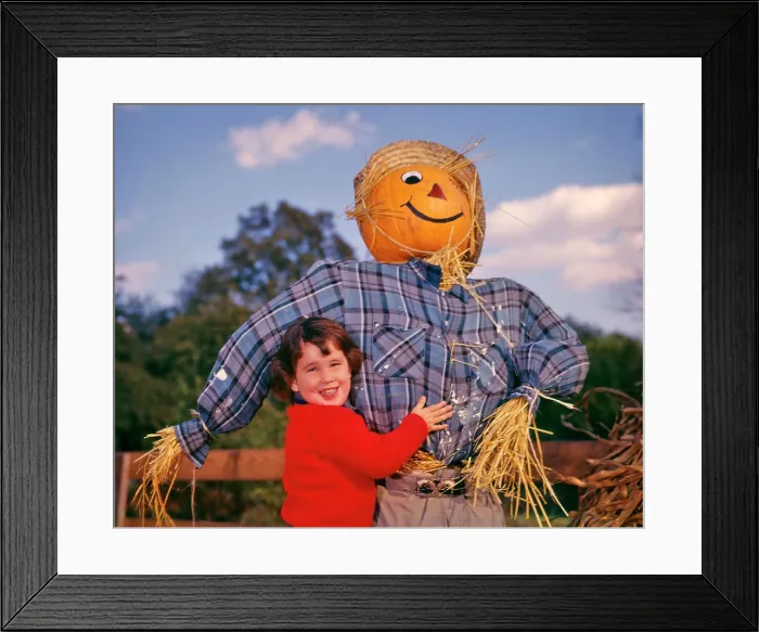 Framed Print : 1950s 1960s SMILING LITTLE BRUNETTE GIRL WEARING RED SWEATER HUGGING SCARECROW SMILING AND LOOKING AT CAMERA