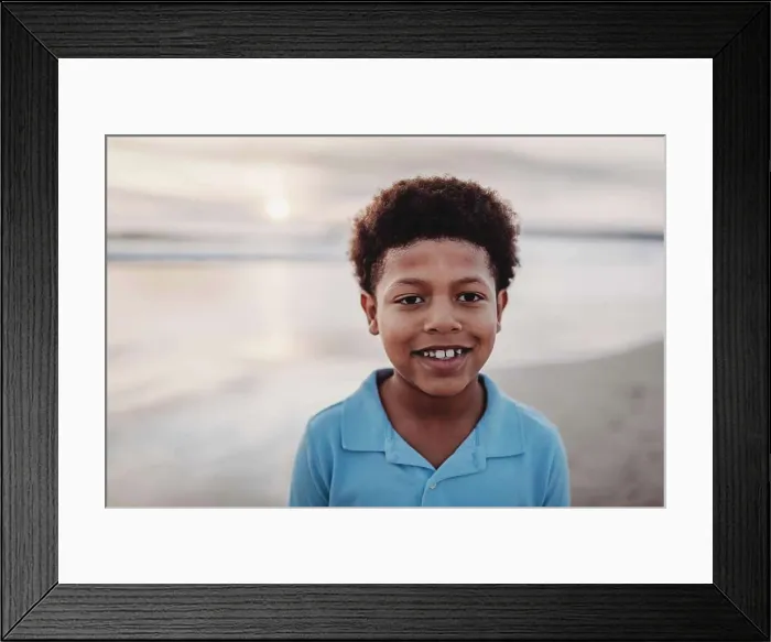 Framed Print : Portrait of young school-aged boy smiling at beach during sunset Framed Print : Portrait of young school-aged boy smiling at beach during sunset