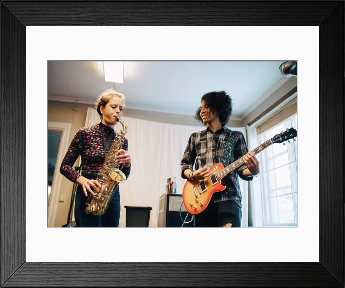 Framed Print : Friends playing saxophone and guitar while practicing at recording studio Framed Print : Friends playing saxophone and guitar while practicing at recording studio