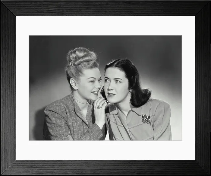 Framed Print : Vintage photograph. Blonde woman telling secret to brunette woman sitting next to her Framed Print : Vintage photograph. Blonde woman telling secret to brunette woman sitting next to her