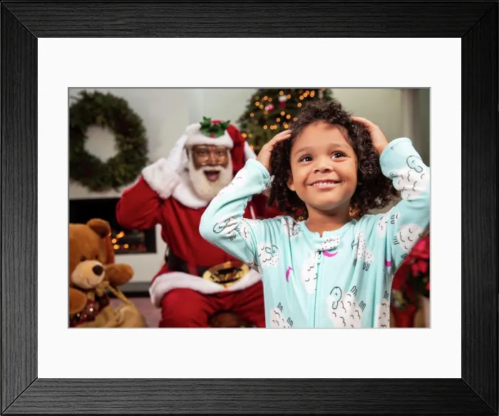Framed Print : Young child in living room with a Christmas background and Santa mimicking her moves behind her. Black Santa Framed Print : Young child in living room with a Christmas background and Santa mimicking her moves behind her. Black Santa