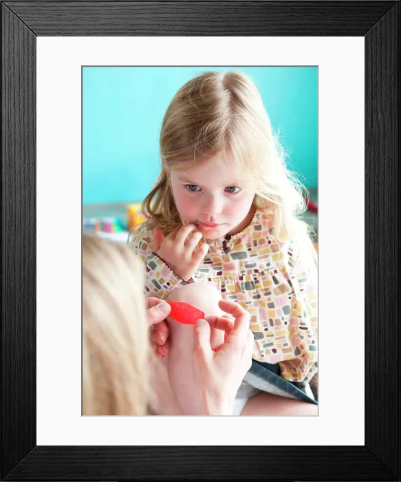 Framed Print : Mother applying band-aid on wounded knee of a girl Framed Print : Mother applying band-aid on wounded knee of a girl