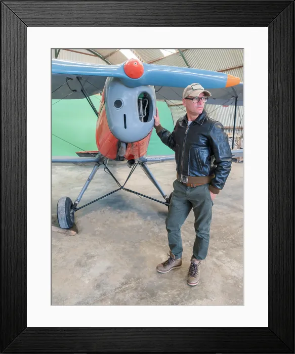 Framed Print : Confident pilot beside retro plane in hangar