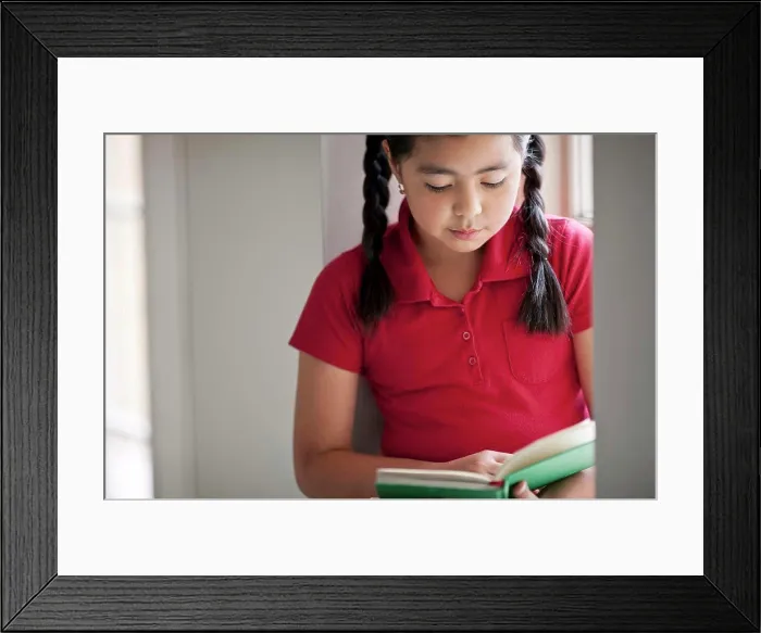 Framed Print : Young schoolgirl reading a book
