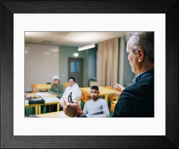 Framed Print : Male teacher gesturing while teaching students in classroom Framed Print : Male teacher gesturing while teaching students in classroom