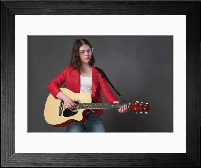 Framed Print : Junge Frau, die eine klassische akustische Gitarre anschlägt