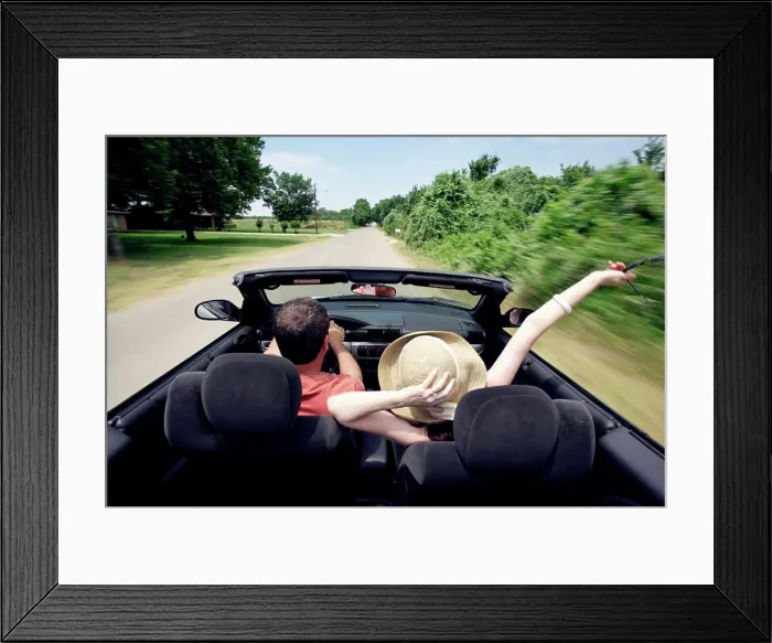 Framed Print : Middle aged baby boomer couple driving down country road in convertible with top down Framed Print : Middle aged baby boomer couple driving down country road in convertible with top down