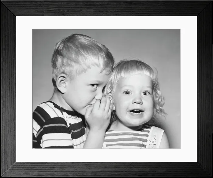 Framed Print : Close-up of a boy whispering to his sister Framed Print : Close-up of a boy whispering to his sister
