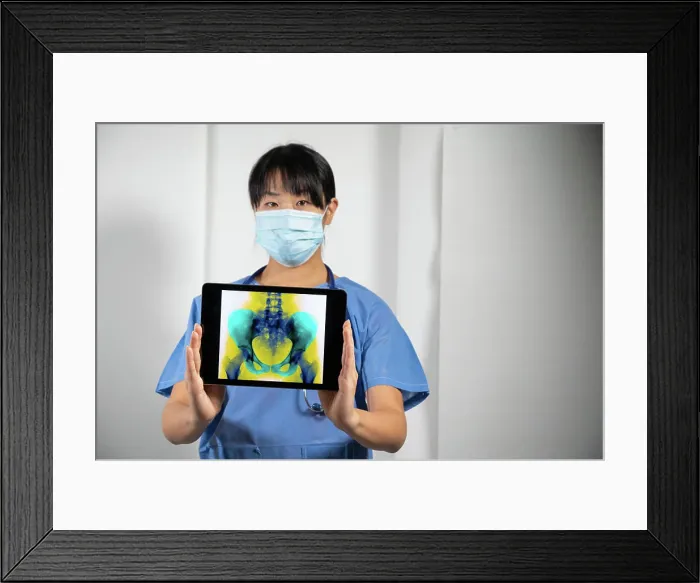 Framed Print : Female doctor holding a screen with x-ray of the pelvis