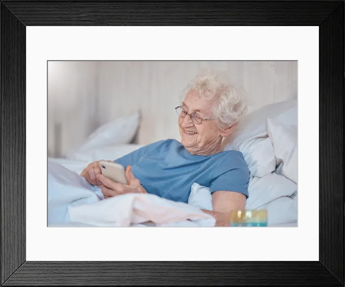 Framed Print : Phone, bed and social media with a senior woman typing a text message while in the bedroom to relax