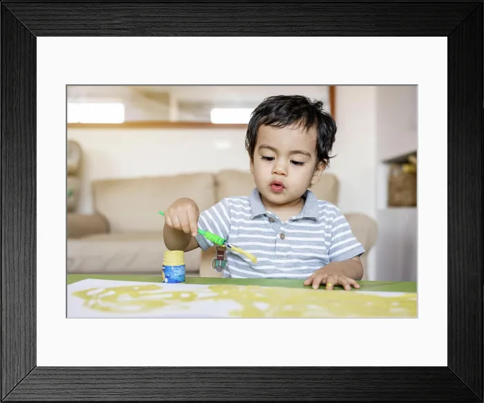 Framed Print : Boy paints with tempera colors paints in her living room