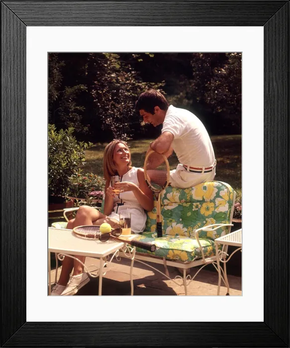 Framed Print : 1970s RELAXING COUPLE SITTING ON PATIO FURNITURE WITH DRINKS BOTH WEARING TENNIS TOGS AFTER PLAYING Framed Print : 1970s RELAXING COUPLE SITTING ON PATIO FURNITURE WITH DRINKS BOTH WEARING TENNIS TOGS AFTER PLAYING