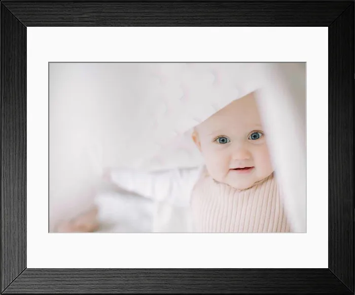 Framed Print : Baby girl looking at the camera while playing under a blanket Framed Print : Baby girl looking at the camera while playing under a blanket