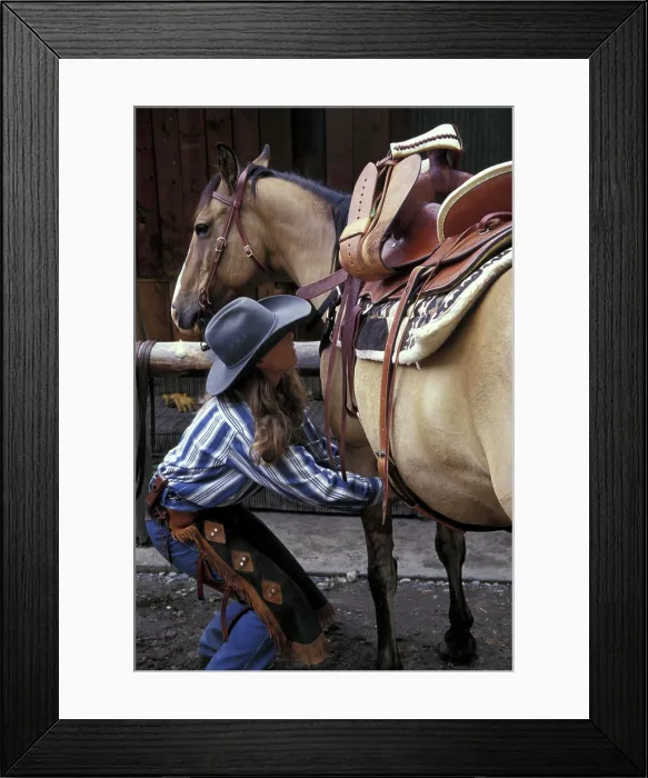 Framed Print : USA, Montana, Boulder River Woman wrangler saddles horse at Boulder River Ranch (MR)