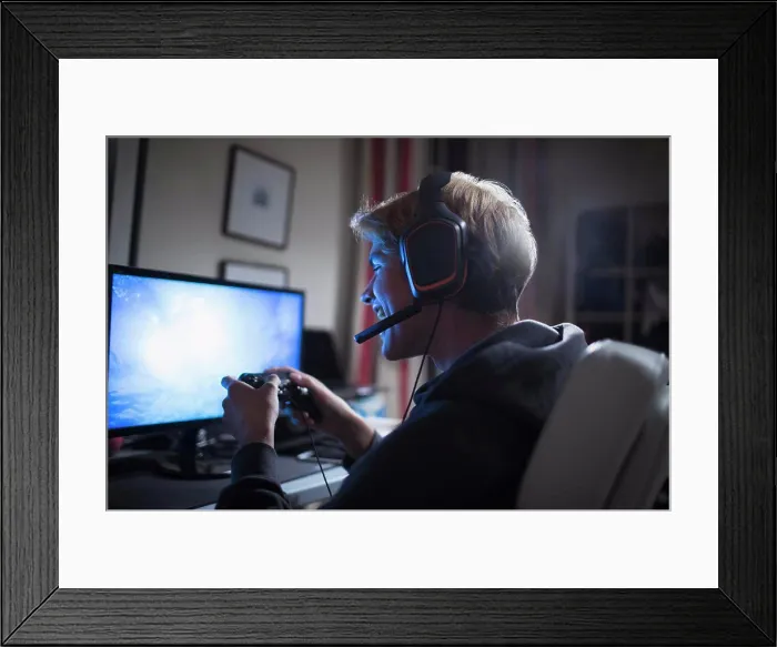 Framed Print : Happy teenage boy with headset playing video game at computer Framed Print : Happy teenage boy with headset playing video game at computer