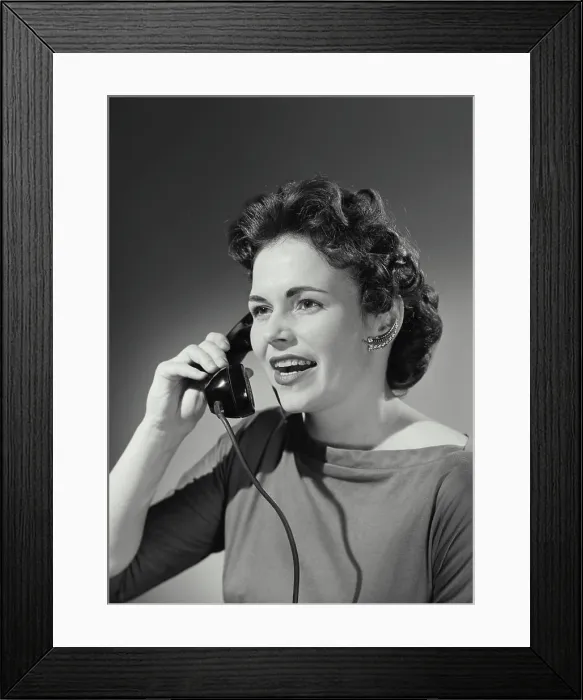 Framed Print : Vintage Photograph. Woman with curled hairstyle holding up telephone receiver having conversation Framed Print : Vintage Photograph. Woman with curled hairstyle holding up telephone receiver having conversation