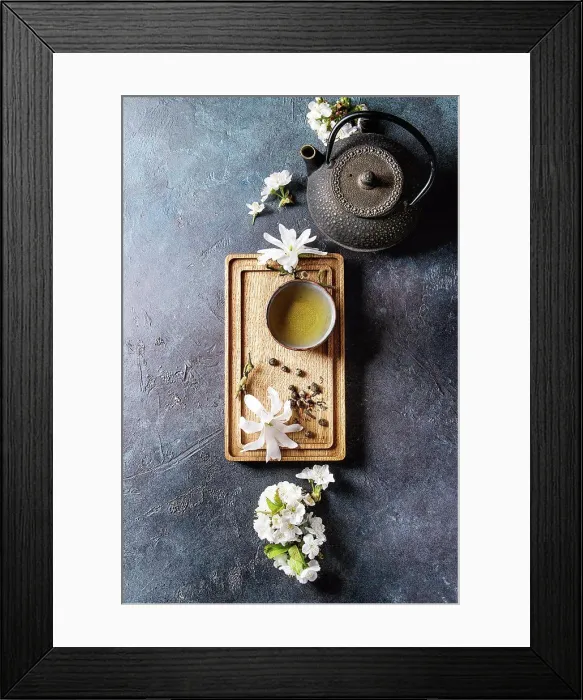 Framed Print : Traditional ceramic cup of hot green tea on wooden board with black iron teapot Framed Print : Traditional ceramic cup of hot green tea on wooden board with black iron teapot